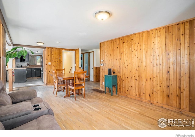 living room featuring wood-type flooring, wood walls, and a healthy amount of sunlight