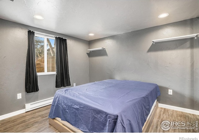 bedroom featuring baseboard heating and hardwood / wood-style floors