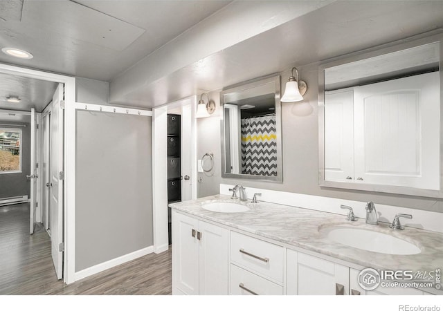 bathroom featuring hardwood / wood-style floors, a baseboard heating unit, and vanity