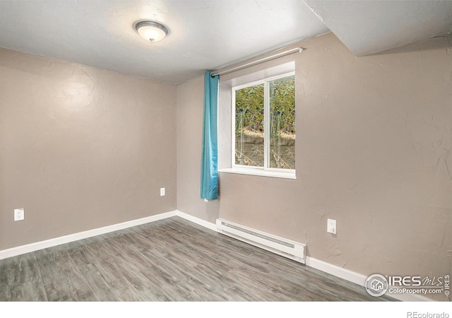 unfurnished room with hardwood / wood-style flooring and baseboard heating