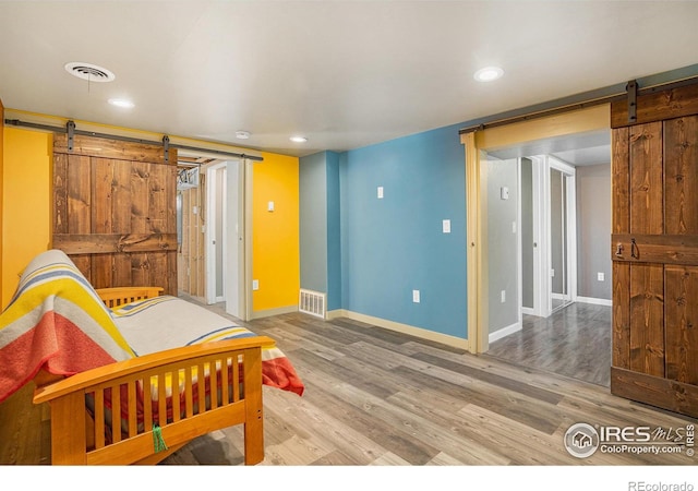 bedroom featuring wood-type flooring and a barn door