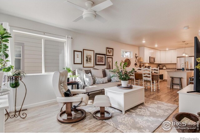 living room featuring light hardwood / wood-style floors and ceiling fan