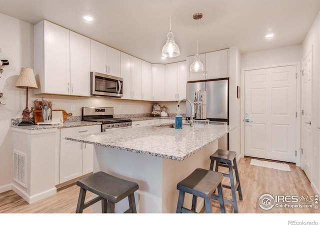 kitchen with appliances with stainless steel finishes, white cabinetry, sink, and light wood-type flooring