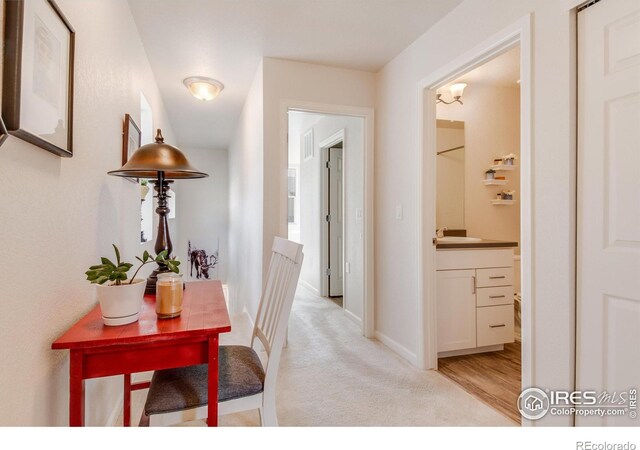 hallway with light carpet and sink