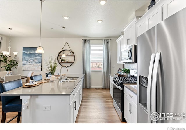 1731 Floating Leaf Dr Unit A, Fort Collins, CO 80528 - kitchen featuring stainless steel appliances, a sink, wood finished floors, a kitchen breakfast bar, and white cabinets