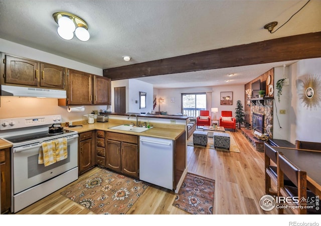 kitchen featuring white appliances, sink, a textured ceiling, kitchen peninsula, and light hardwood / wood-style floors