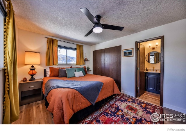 bedroom with ensuite bath, sink, hardwood / wood-style floors, a textured ceiling, and ceiling fan