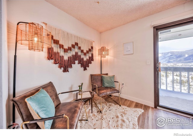 sitting room with hardwood / wood-style floors, a mountain view, and a textured ceiling