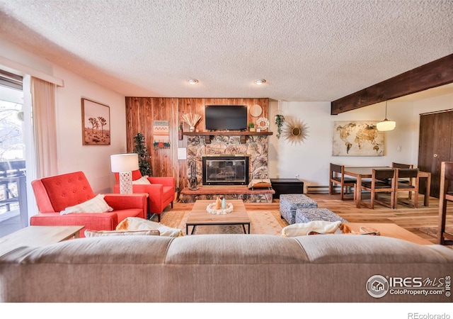 living room with a textured ceiling, beam ceiling, wood-type flooring, and a fireplace