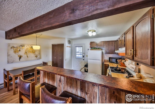 kitchen with hanging light fixtures, stove, light wood-type flooring, beamed ceiling, and white refrigerator