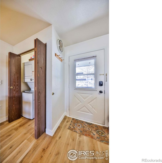 doorway featuring light hardwood / wood-style flooring and stacked washer and clothes dryer