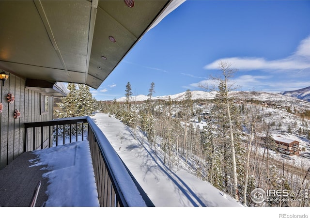 snow covered back of property with a mountain view