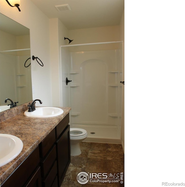 bathroom with vanity, toilet, and a shower