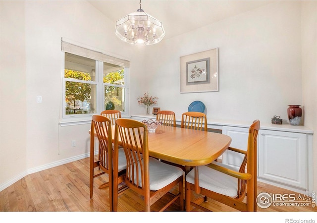 dining space featuring an inviting chandelier, lofted ceiling, and light hardwood / wood-style floors