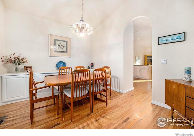 dining room featuring high vaulted ceiling, a chandelier, and light wood-type flooring