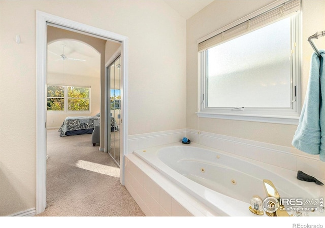 bathroom featuring a relaxing tiled tub and ceiling fan