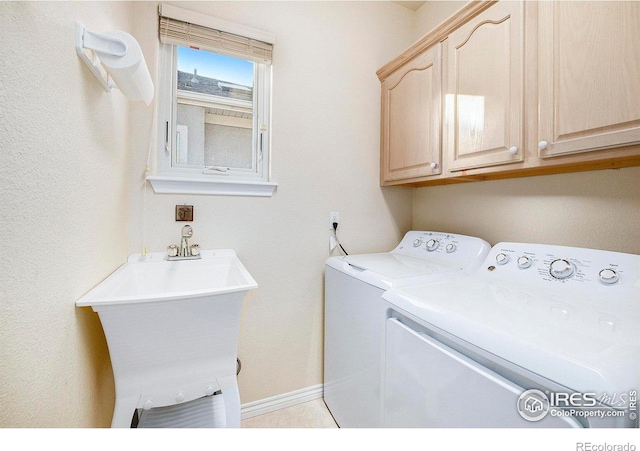 clothes washing area with sink, cabinets, and washer and clothes dryer