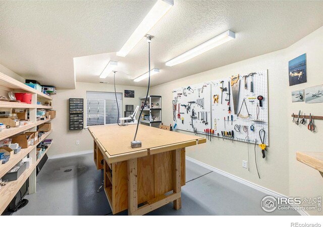 interior space featuring a textured ceiling, a workshop area, and concrete floors