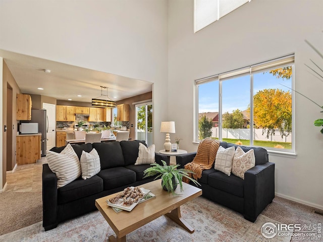 living room with a high ceiling, a notable chandelier, and light colored carpet