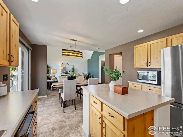 kitchen featuring light brown cabinets, a kitchen island, appliances with stainless steel finishes, a textured ceiling, and decorative light fixtures