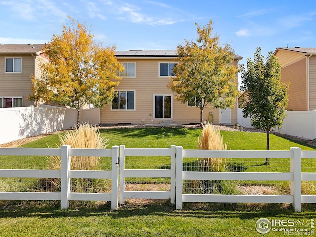 view of front of property with a front yard and solar panels