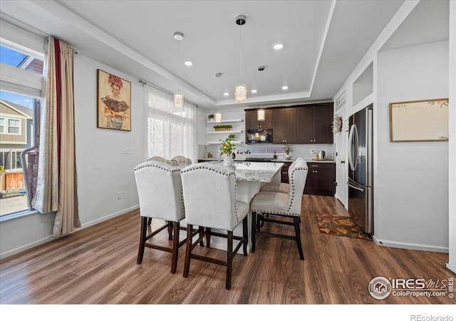 dining space with a raised ceiling and dark hardwood / wood-style floors