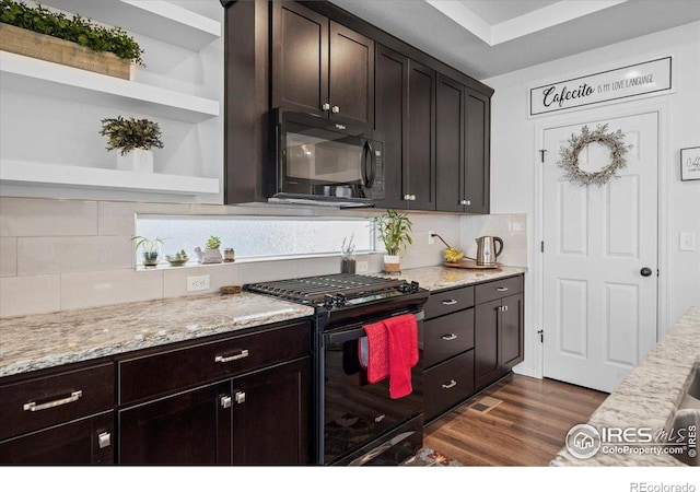 kitchen featuring light stone countertops, black appliances, backsplash, dark brown cabinets, and dark hardwood / wood-style flooring