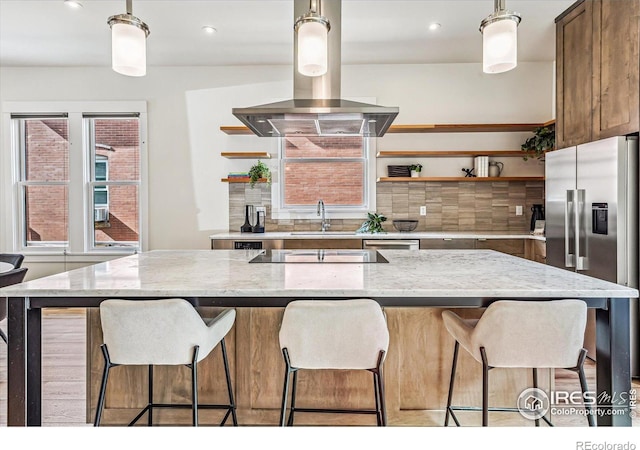 kitchen featuring island range hood, decorative backsplash, sink, light stone countertops, and appliances with stainless steel finishes