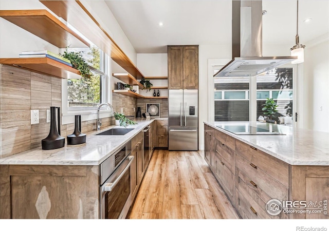 kitchen with sink, island exhaust hood, hanging light fixtures, stainless steel appliances, and decorative backsplash