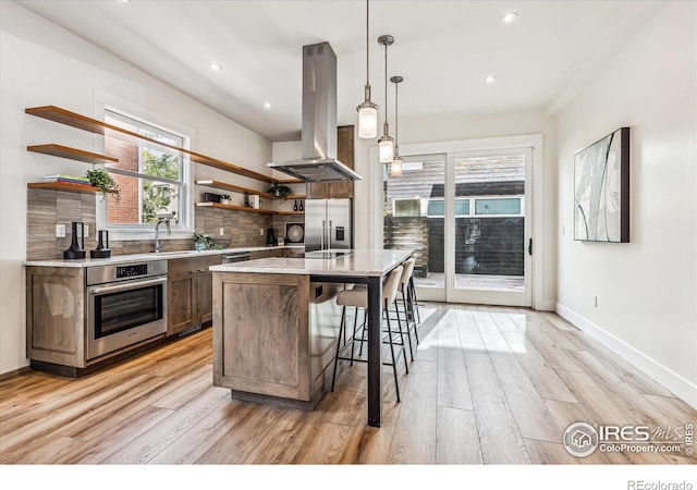 kitchen featuring a kitchen island, wall chimney range hood, backsplash, pendant lighting, and appliances with stainless steel finishes