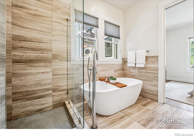 bathroom with tile walls, separate shower and tub, and tile patterned flooring