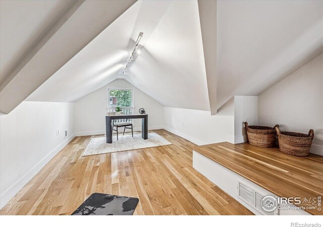 additional living space with hardwood / wood-style flooring and lofted ceiling