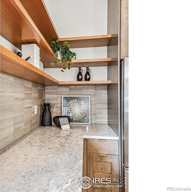 interior space with decorative backsplash and stainless steel fridge