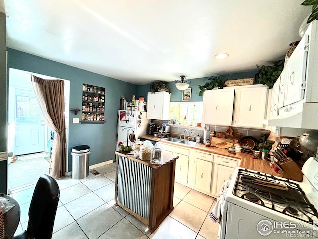 kitchen featuring light tile patterned flooring, sink, white cabinetry, and white appliances