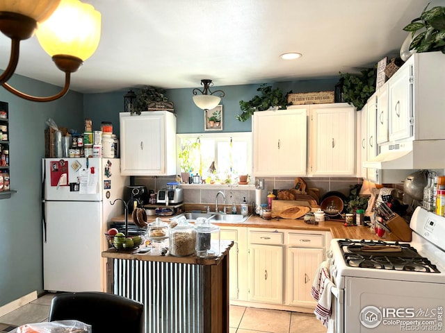 kitchen featuring white appliances, decorative light fixtures, white cabinetry, sink, and light tile patterned flooring