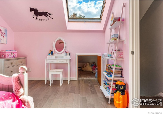 playroom featuring vaulted ceiling with skylight and wood-type flooring