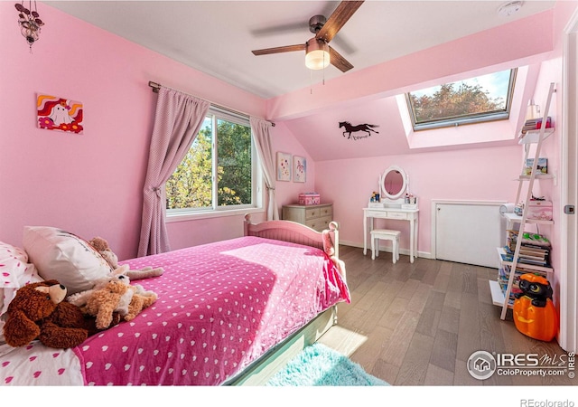 bedroom featuring vaulted ceiling with skylight, wood-type flooring, and ceiling fan