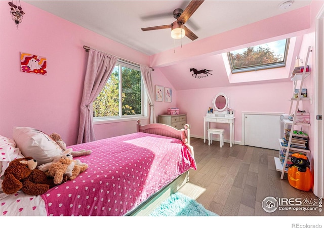 bedroom with baseboards, wood finished floors, ceiling fan, and vaulted ceiling with skylight