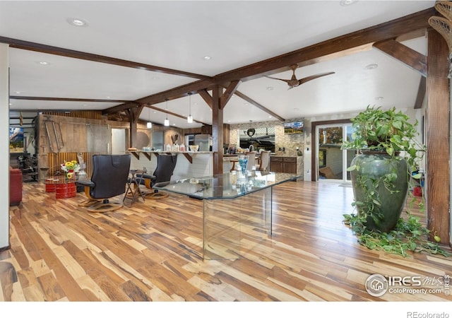 living room featuring wood walls, light hardwood / wood-style flooring, lofted ceiling with beams, and ceiling fan