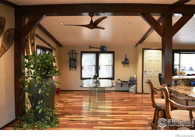 dining area featuring beamed ceiling, wood-type flooring, plenty of natural light, and ceiling fan