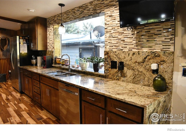 kitchen with tasteful backsplash, sink, stainless steel dishwasher, dark wood-type flooring, and light stone counters