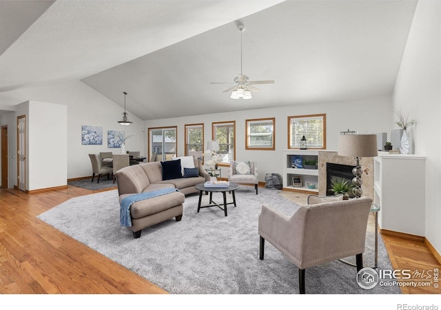 living room featuring ceiling fan, hardwood / wood-style flooring, vaulted ceiling, and a tile fireplace