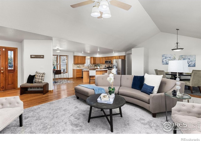 living room with ceiling fan, lofted ceiling, and light hardwood / wood-style flooring