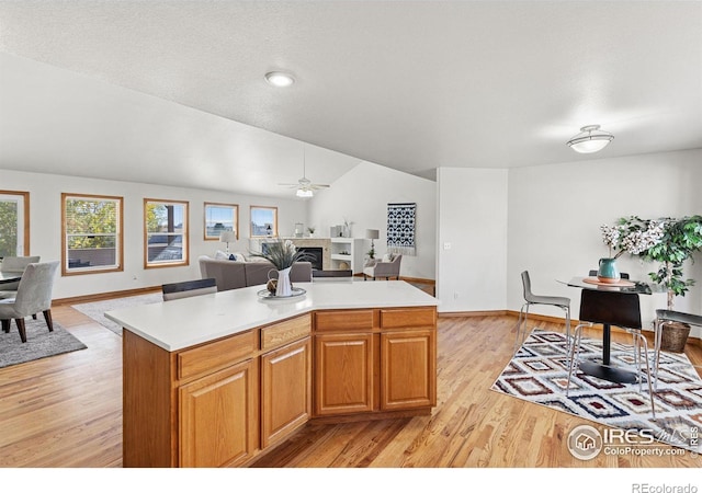 kitchen with a textured ceiling, a center island, light hardwood / wood-style floors, ceiling fan, and lofted ceiling