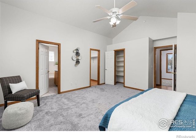 carpeted bedroom featuring lofted ceiling, ensuite bath, a walk in closet, and ceiling fan