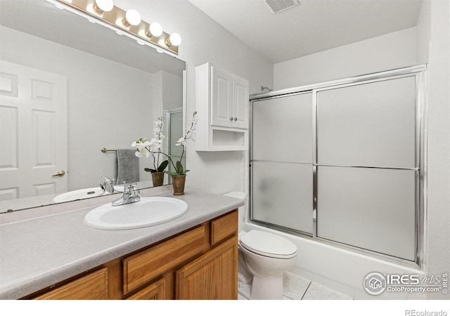 full bathroom with vanity, combined bath / shower with glass door, toilet, and tile patterned floors