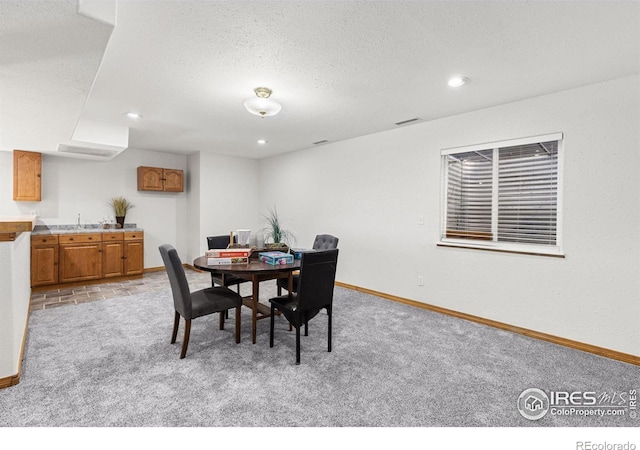 dining room featuring a textured ceiling, sink, and light colored carpet