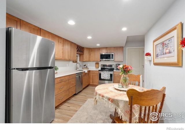 kitchen with sink, stainless steel appliances, and light hardwood / wood-style floors