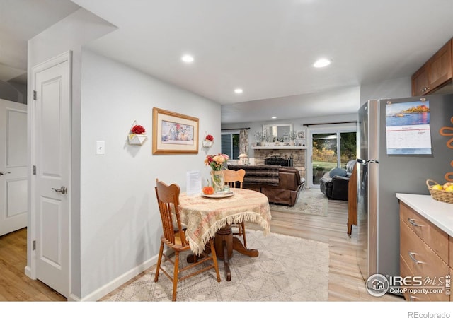 dining room with light hardwood / wood-style flooring and a stone fireplace