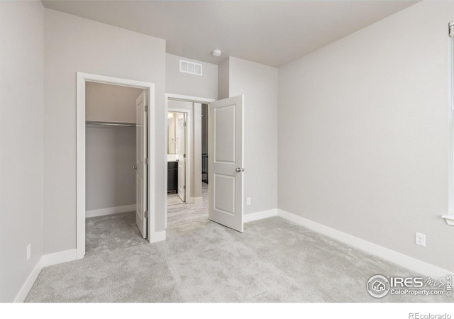 unfurnished bedroom with light carpet, a closet, and a walk in closet